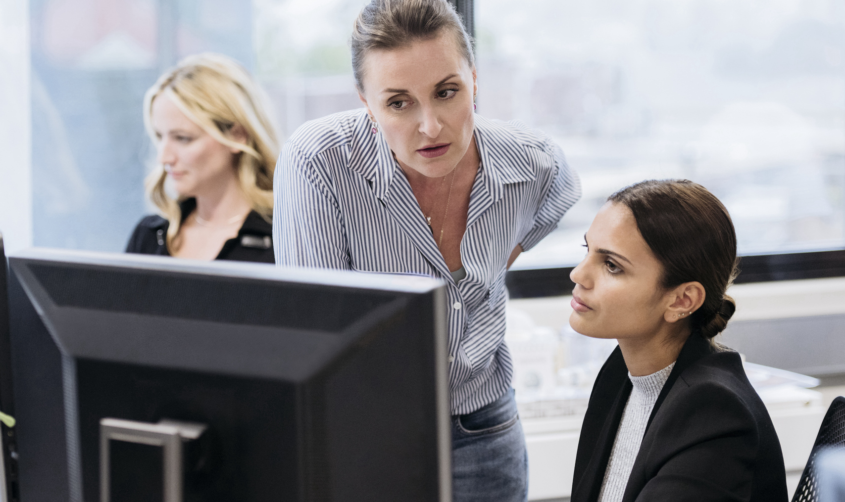 Co-workers discussing an issue at an office computer.
